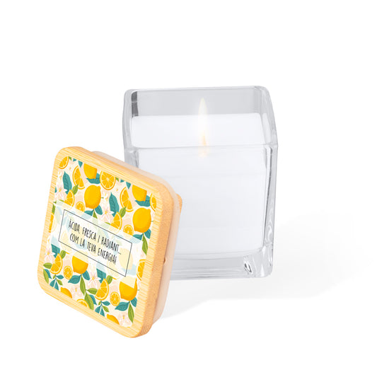 Vela aromática en tarro de cristal cuadrado con tapa de bambú. Diseño impreso: fondo color blanco con limones, flores de limonero y hojas estilo acuarela. En el centro un rectángulo blanco con la frase: "Àcida, fresca i radiant... com la teva energia"