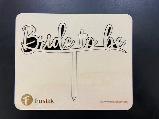 Detalle del topper para tarta hecho con las palabras "Bride to be" tallada a láser en madera. Montado sobre una base de madera para evitar roturas de transporte. Tiene una patita para poderlo clavar en la tarta.