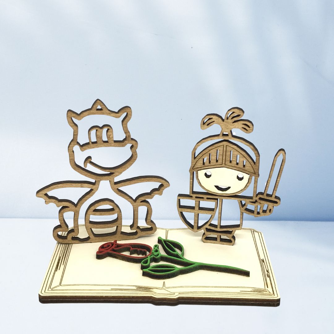 Figura decorativa de madera con el caballero y el dragón de Sant Jordi sobre una base en forma de libro y una rosa, pieza artesanal sostenible ideal para regalar o decorar en la Diada de Sant Jordi.