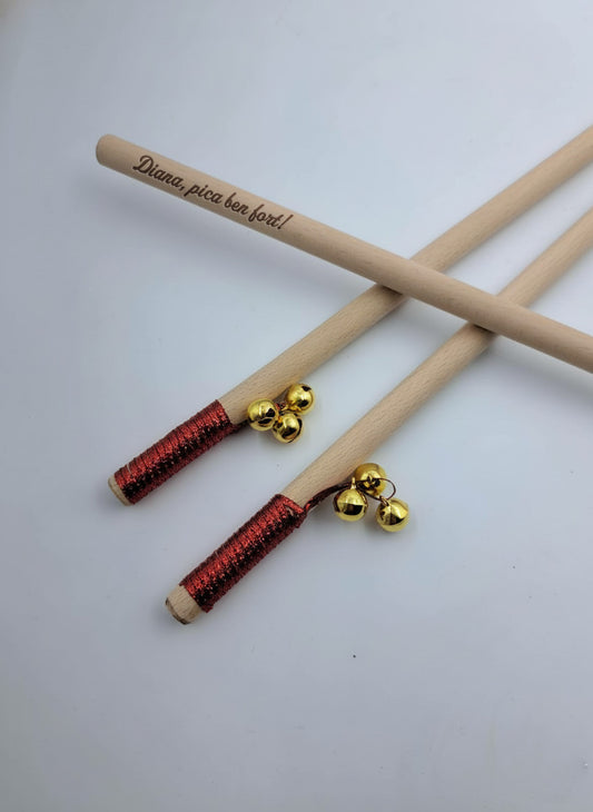 Tres bastones de madera con tres cascabeles dorados cada uno y una cinta roja ornamental personalizados con grabado láser.