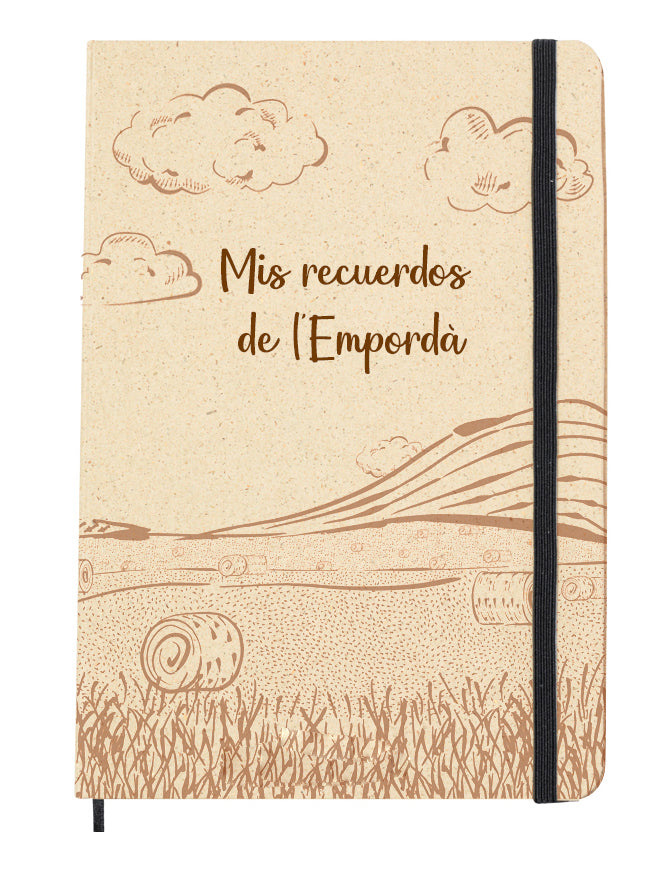 Portada del bloc de notas de hierba reciclada con goma elástica para mantenerla cerrada. Diseño de la portada: Ilustración muy simple, estilo pinceladas de un campo con balas de paja y un cielo con nubes, todo de tono marrón claro. Acompaña la frase "Mis recuerdos de l'Empordà"