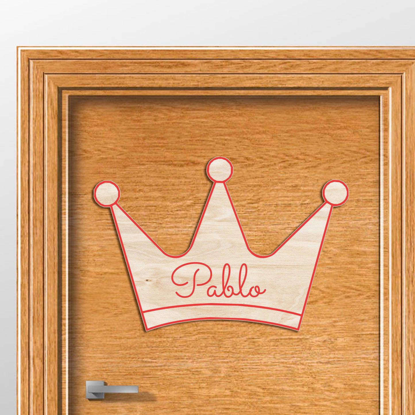 Corona de madera con tres puntas, silueteada en relieve y color y personalizada con el nombre del rey de la casa a conjunto.