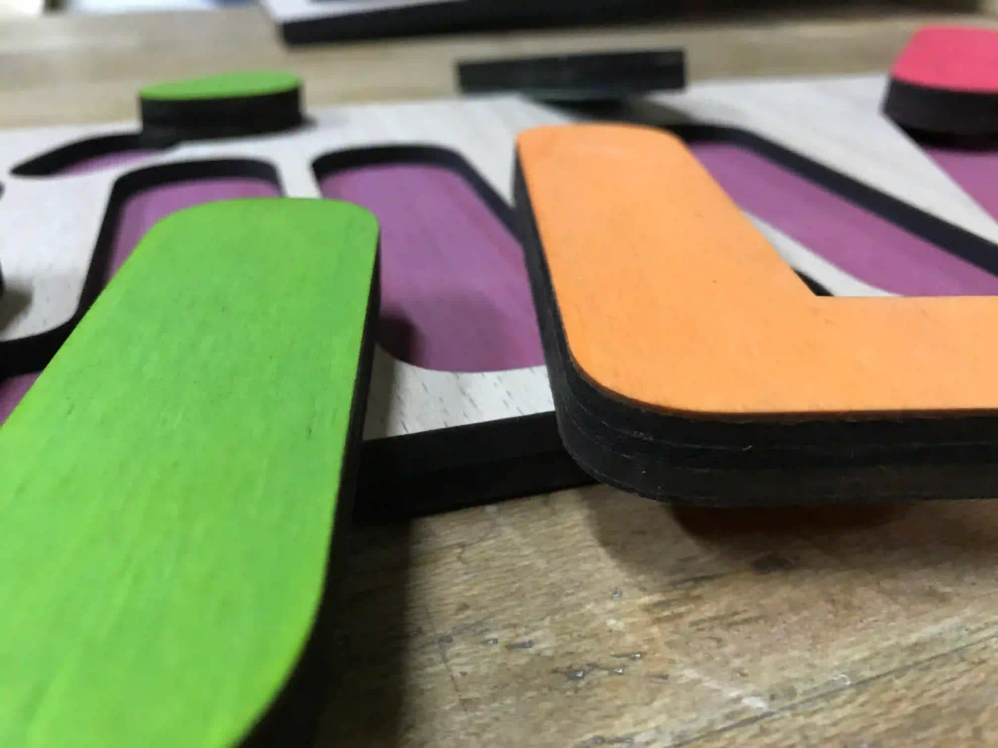 Juego infantil de madera para encajar letras. Personalizado con el nombre del niño o niña, las letras se pintan aleatoriamente para que combinen en conjunto. Detalle