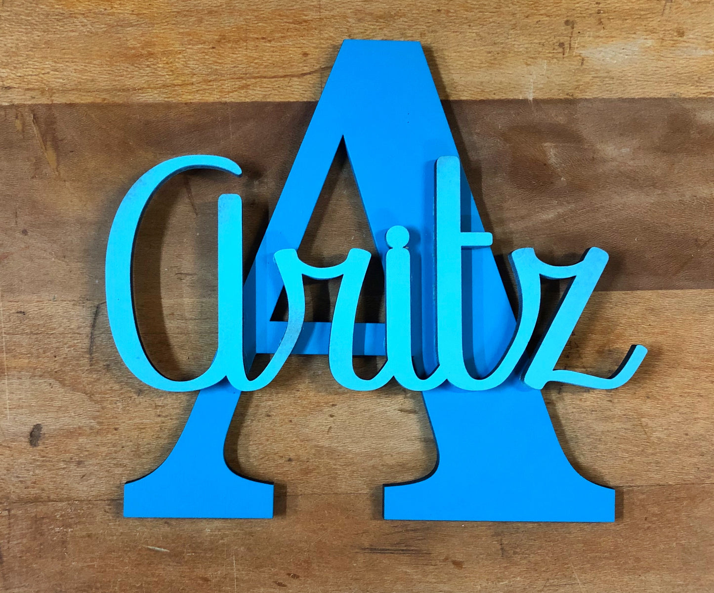 Nombre decorativo de madera, troquelado y montado sobre inicial de madera de chopo pintadas a dos colores para mayor contraste. Combinación de colores de la misma gama