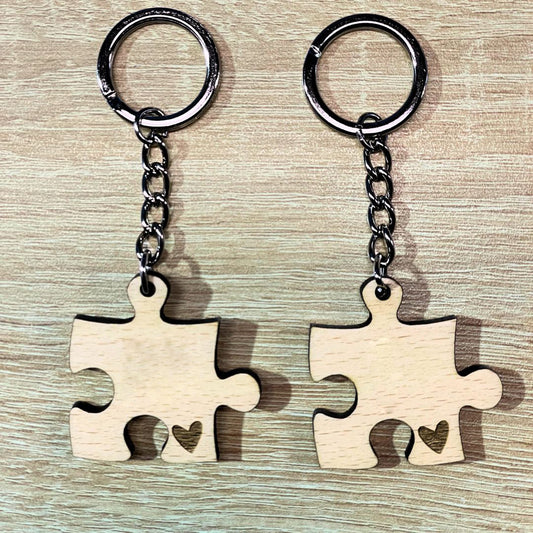 Pack de dos llaveros de madera de haya en forma de pieza de puzle, grabados a láser con las iniciales de la pareja y un detalle en forma de corazón.