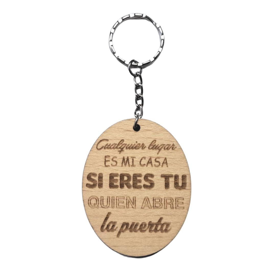 Llavero de madera de haya ovalado con la frase grabada a láser: Cualquier lugar es mi casa si eres tú quien abre la puerta.