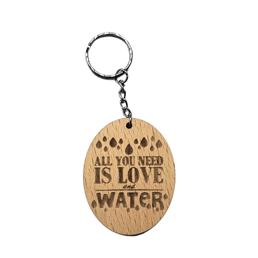 Llavero de madera de haya ovalado con la frase grabada a láser: All you need is love and water