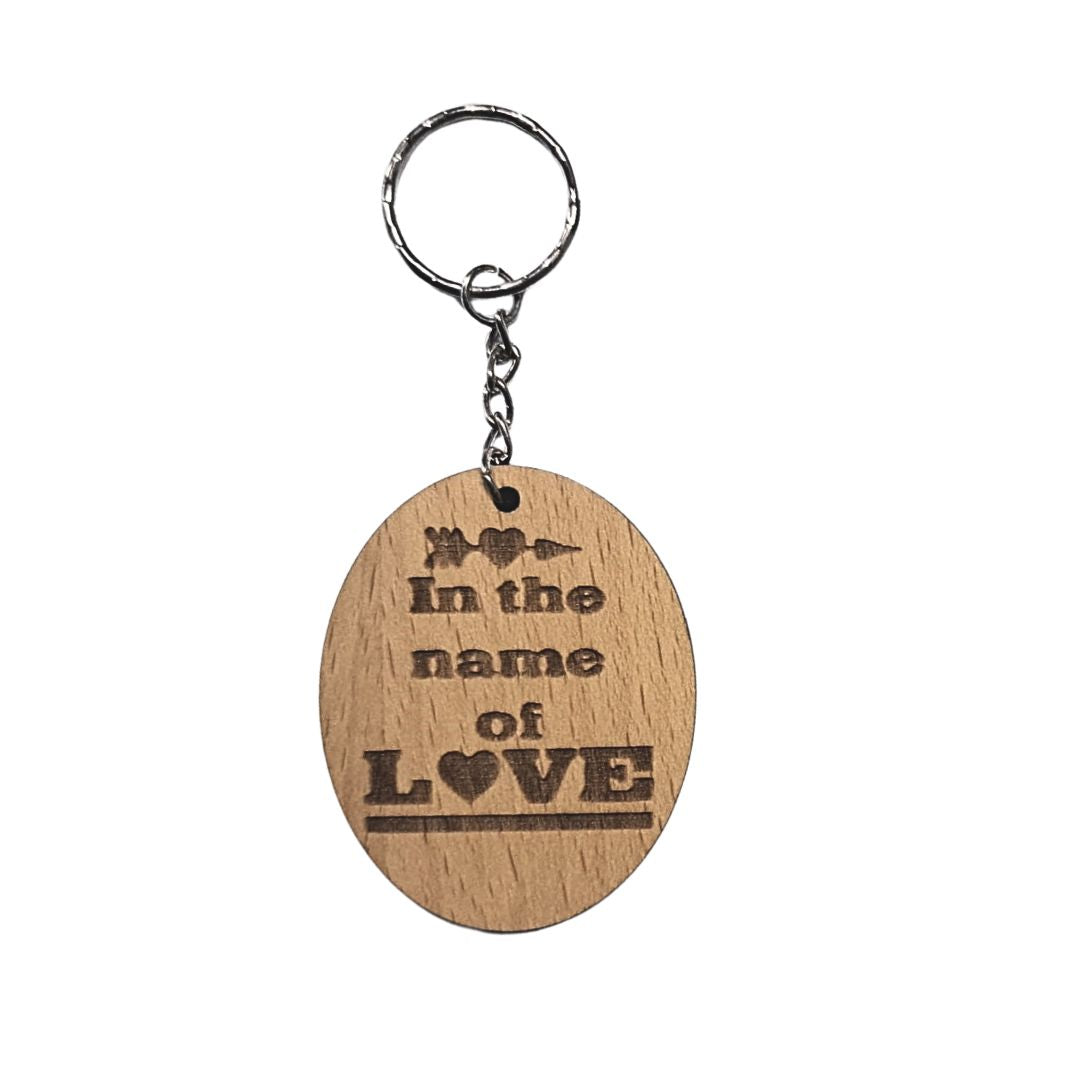 Llavero de madera de haya ovalado con la frase grabada a láser: In the name of love