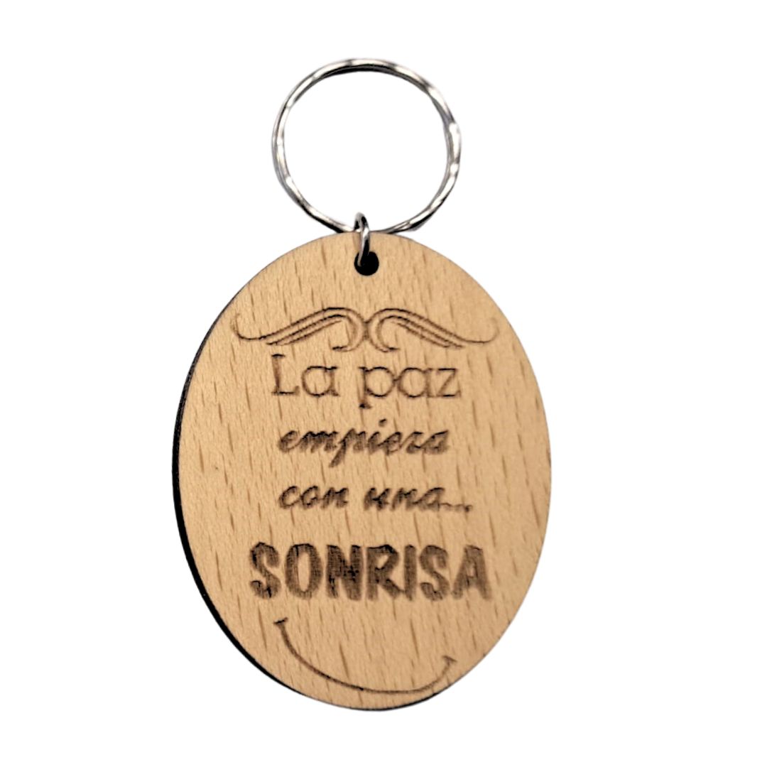 Llavero de madera de haya ovalado con la frase grabada a láser: La paz empieza con una sonrisa
