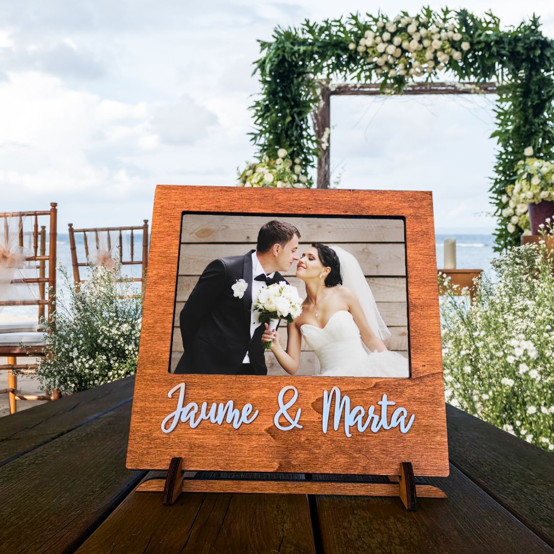 Marco de fotos de madera con espacio para una foto de 15x20cm. Personalizado con los nombres de la pareja en metacrilato blanco en relieve.