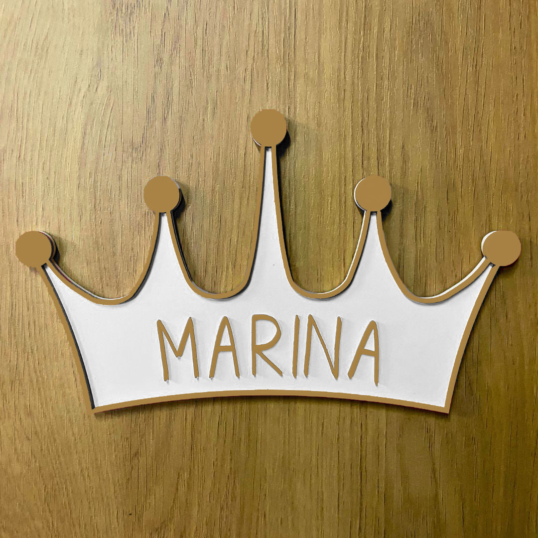Corona de madera con cinco puntas, detalle en relieve y color en el contorno de la pieza. Personalizada con el nombre de la reina de la casa a conjunto con el relieve. Ejemplo en color dorado.