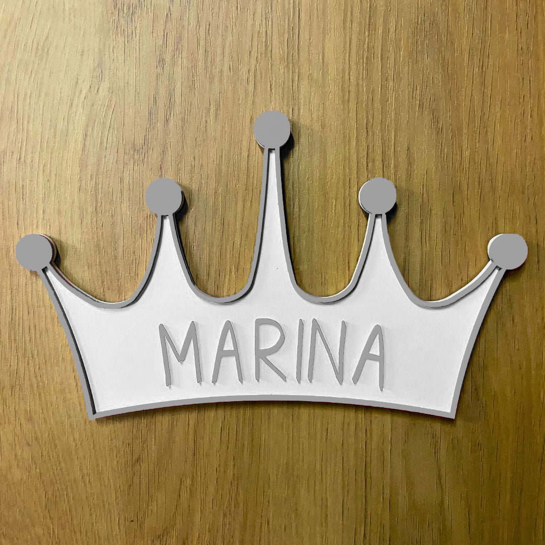 Corona de madera con cinco puntas, detalle en relieve y color en el contorno de la pieza. Personalizada con el nombre de la reina de la casa a conjunto con el relieve. Ejemplo en color plateado.