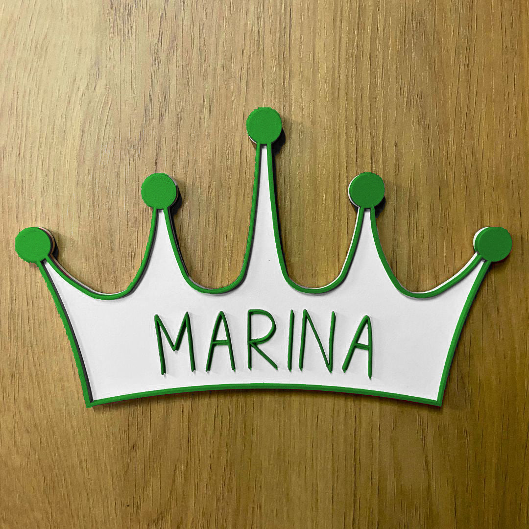 Corona de madera con cinco puntas, detalle en relieve y color en el contorno de la pieza. Personalizada con el nombre de la reina de la casa a conjunto con el relieve. Ejemplo en color verde.