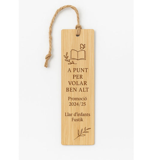 Punto de libro de bambú grabado con un dibujo simple de un libro y una mariposa y el texto "A punt per volar ben alt. Promoció 2024/25. Llar d'infants Fustik"