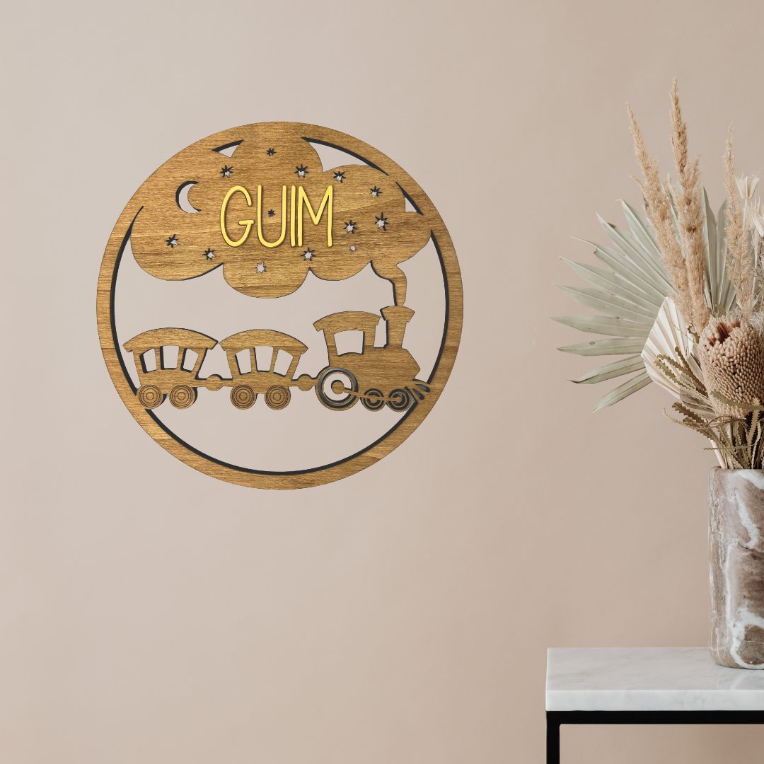 Placa de madera circular para colgar en la pared con detalle de tren troquelado y personalizada con el nombre de la niña o niño en madera de color.