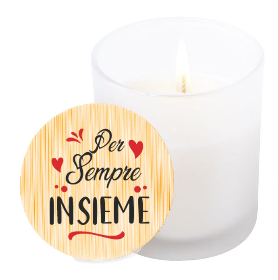 Vela aromática de vainilla en tarro de cristal translúcido con tapa de bambú y mensaje impreso en colores rojo y negro. Per Sempre insieme