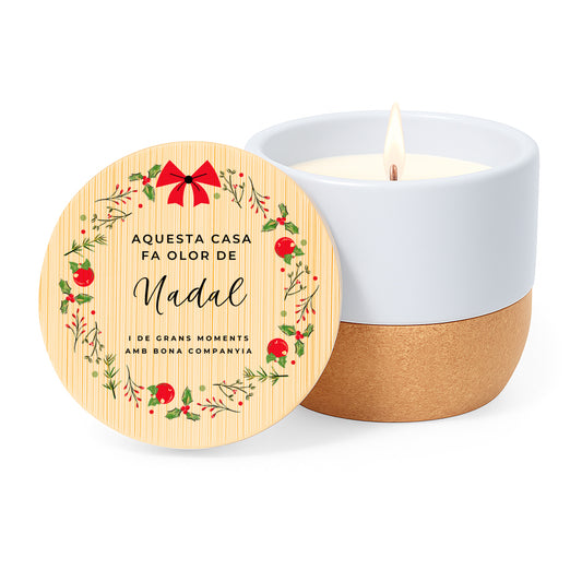 Vela con aroma de lino en tarro de cerámica con base de corcho y tapa de bambú impresa con diseño simple navideño y la frase "Aquesta casa fa olor de Nadal i de grans moments amb bona companyia"