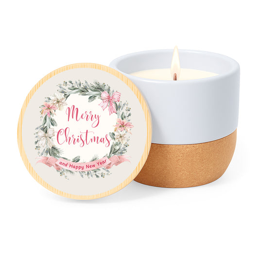 Vela con aroma de lino en tarro de cerámica y base de corcho. Tapa de bambú impresa con diseño clasico de navidad: corona de flores en tonos rosa y la frase Merry Christmas and Happy New Year