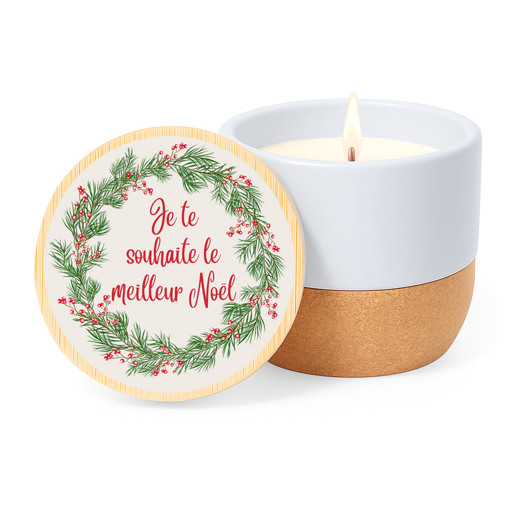 Vela con aroma de lino en tarro de cerámica y base de corcho. Tapa de bambú impresa con diseño de corona vegetal y la frase Je te souhaite le meilleur Noël