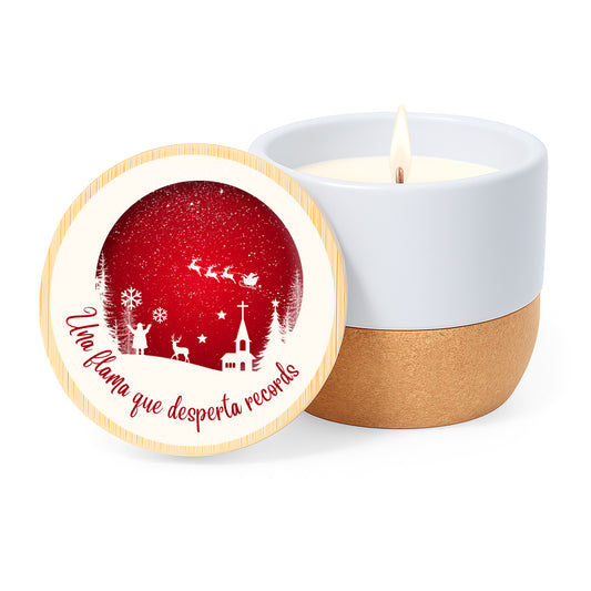 Vela con aroma de lino en tarro de cerámica con base de corcho y tapa de bambú impresa con diseño en blanco y rojo navideño con la silueta de Papá Noel con su trineo y la frase "Una flama que desperta records"
