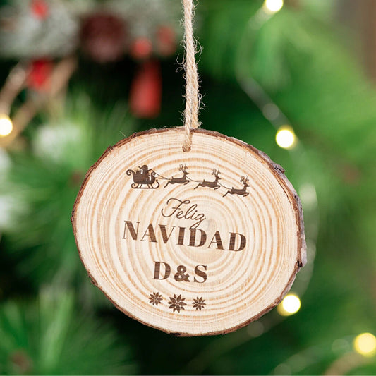 Decoración para el árbol de Navidad en forma de rodaja de madera rústica grabada a láser por una cara, acabado con cordel rústico y una bola de madera a modo de adorno.