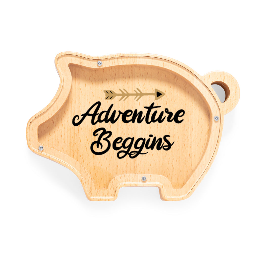 Hucha de madera con forma de cerdito y tapa de metacrilato impresa. Mensaje "Adventure Beggins"