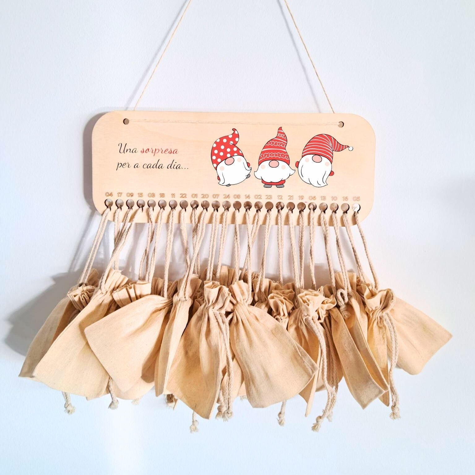 Calendario de adviento de madera rectangular, impreso a todo color con impresión directa, con 24 agujeros donde cuelgan 24 saquitos de tela para rellenar con sorpresas