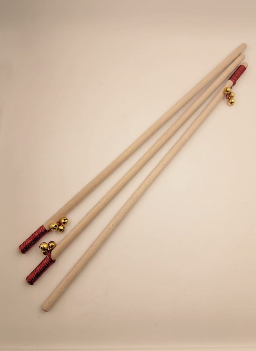 Tres bastones de madera con tres cascabeles dorados cada uno y una cinta roja ornamental a punto de ser personalizados con grabado láser. 