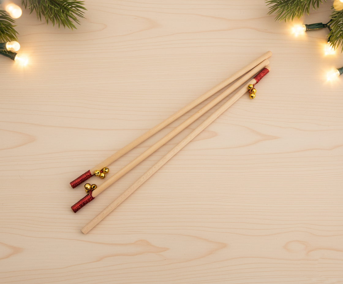 Tres bastones de madera con tres cascabeles dorados cada uno y una cinta roja ornamental a punto de ser personalizados con grabado láser. 
