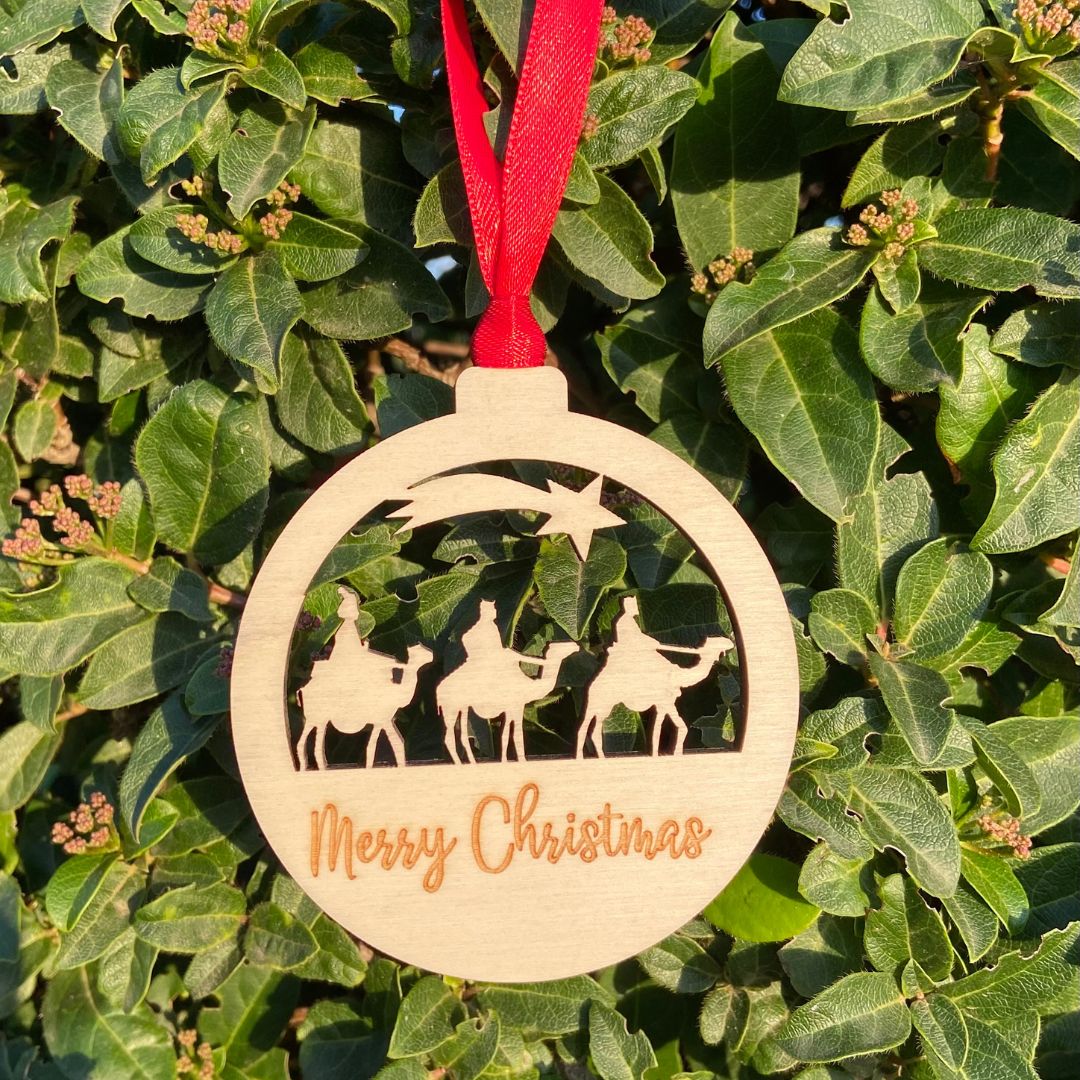 Bola de madera para el árbol de Navidad con la silueta de los Reyes Magos troquelada y  personalizada con el nombre que elijas grabado a láser. Incluye cinta roja para colgar del árbol