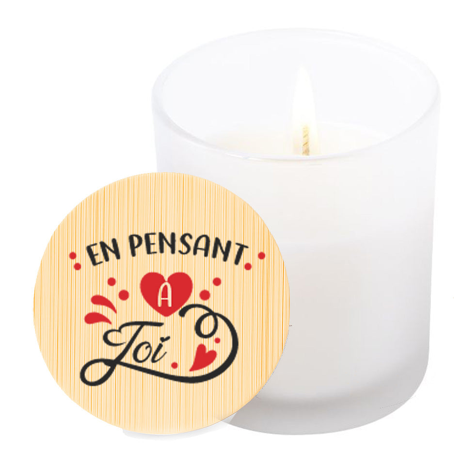 Vela aromática de vainilla en tarro de cristal translúcido con tapa de bambú y mensaje impreso en colores rojo y negro. En pensant a toi