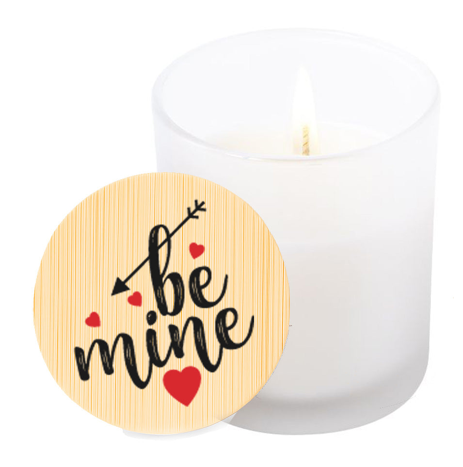 Vela aromática de vainilla en tarro de cristal translúcido con tapa de bambú y mensaje impreso en colores rojo y negro. Be Mine.