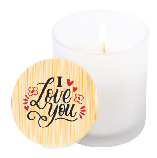 Vela aromática de vainilla en tarro de cristal translúcido con tapa de bambú y mensaje impreso en colores rojo y negro. I love you