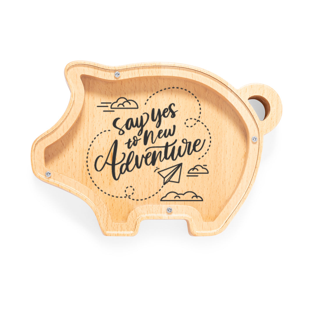 Hucha de madera con forma de cerdito y tapa de metacrilato impresa. Mensaje "Say yes to new adventure"