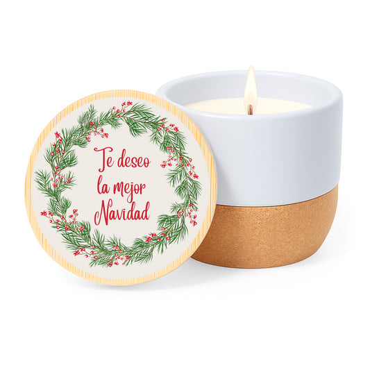 Vela con aroma de lino en tarro de cerámica y base de corcho. Tapa de bambú impresa con diseño de corona vegetal y la frase Te deseo la mejor Navidad