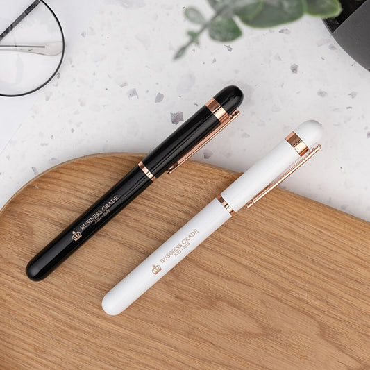 Bolígrafo roller de aluminio con detalles rosados y tinta azul. Color blanco o negro. Personalizable con grabado láser. Ideal para regalos elegantes y detalles para eventos.