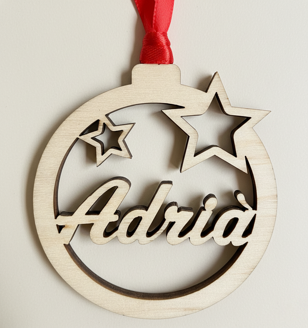 Bola de navidad de madera formada por un círculo y dos estrellas troqueladas y el nombre en el centro. Ligera y resistente. Incluye cinta roja para colgar en el árbol. 