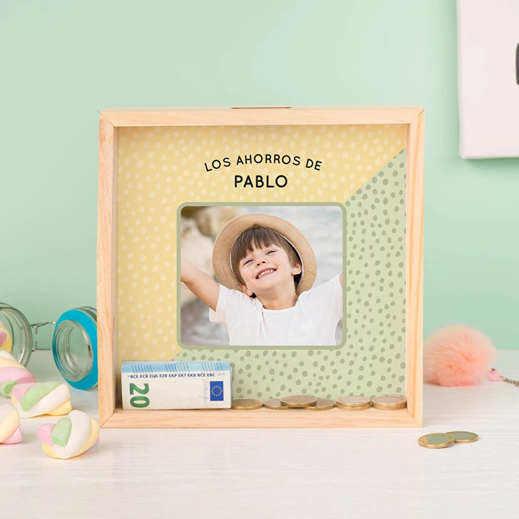 hucha de madera quadrada con frontal de metacrilato que permite ver la impresión del fondo, una foto de un niño y la frase Los Ahorros de Pablo