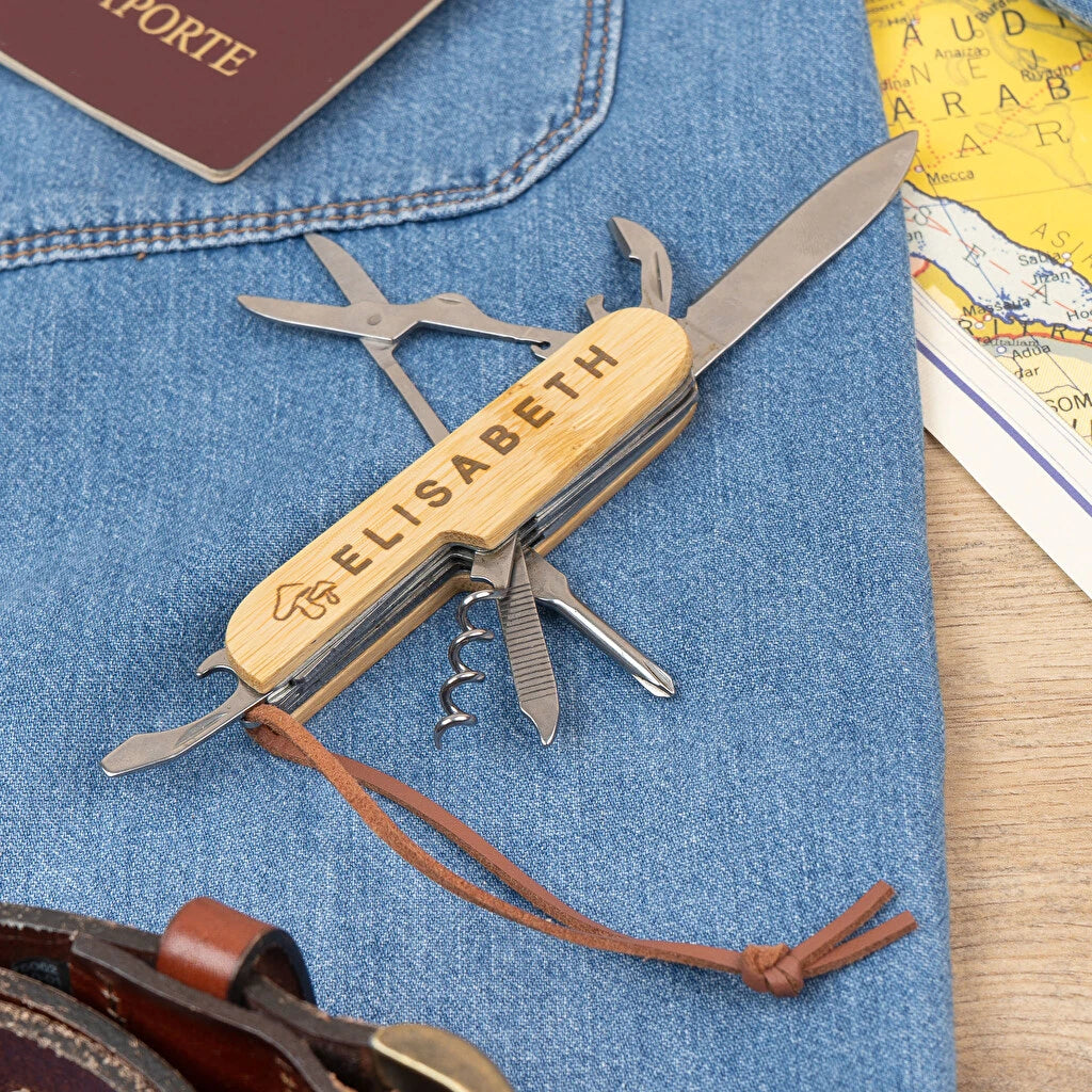 Navaja multiusos desplegada con nombre grabado a láser en la empuñadura. Tijeras, abrebotellas, cuchilla, sacacorchos, lima, destornillador a la vista. 