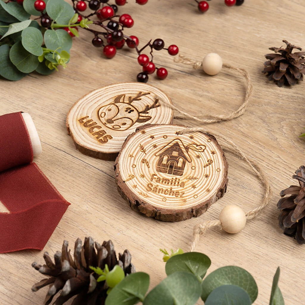 Decoración para el árbol de Navidad en forma de rodaja de madera natural y rústica grabada a láser por una cara, acabado con cordel rústico y una bola de madera a modo de adorno. 