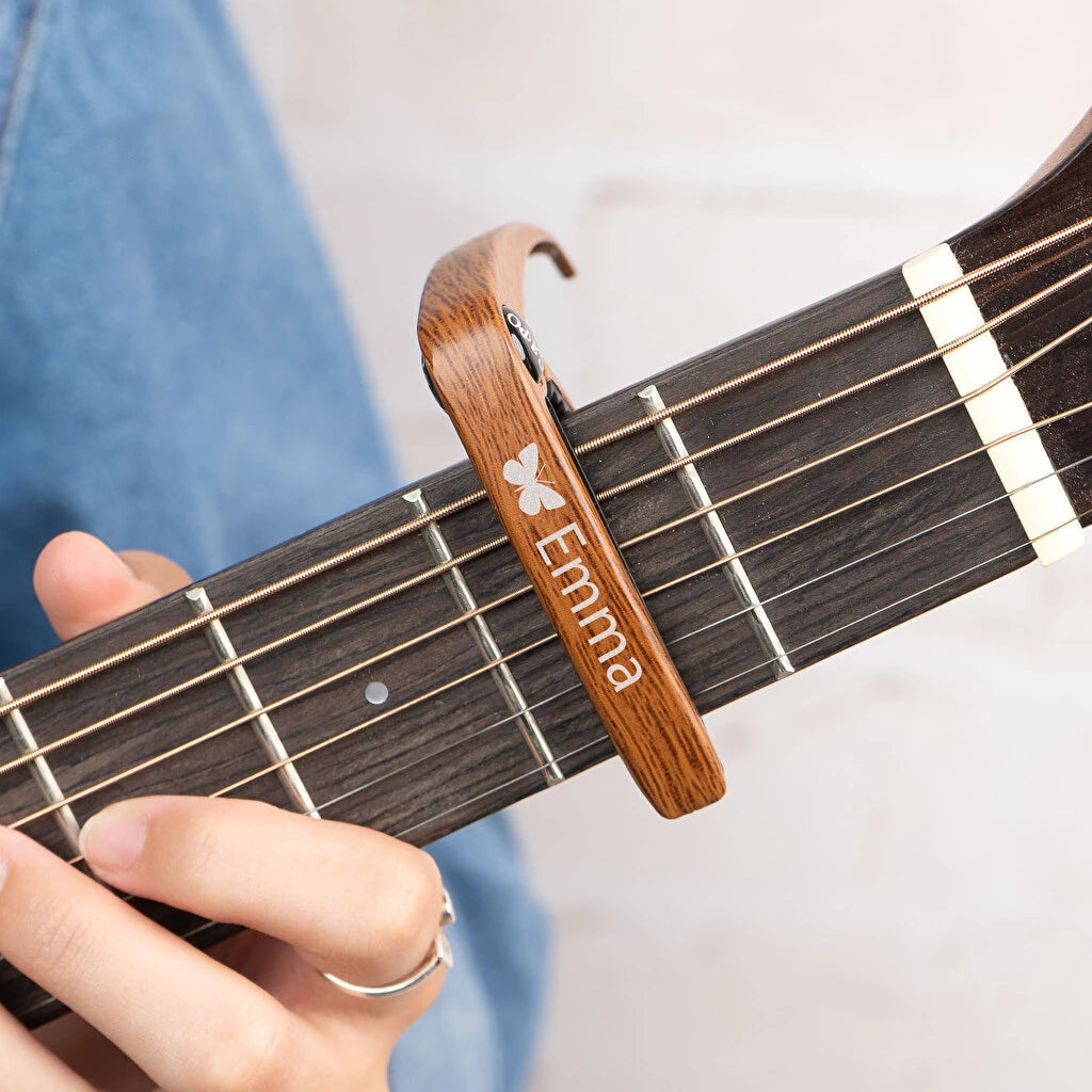 Cejilla de guitarra personalizada con grabado. Fabricada en metal con acolchado protector para el mástil. Acabado madera