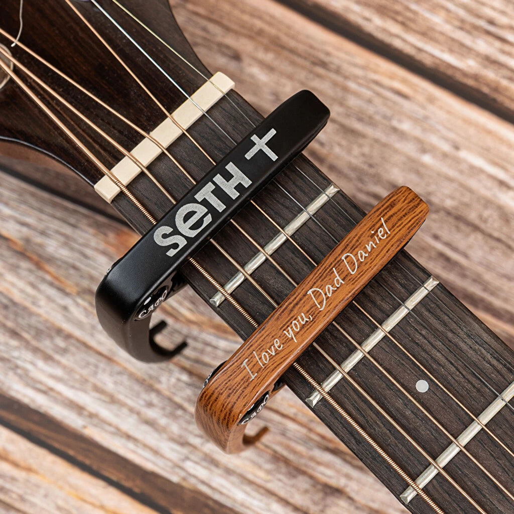 Cejilla de guitarra personalizada con grabado. Fabricada en metal con acolchado protector para el mástil. Dos acabados distintos